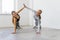 Young attractive women practicing yoga together giving high five holding hands and standing in side plank pose on rubber mats at