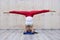 Young attractive yogi woman practicing yoga concept, standing in variation of Pincha Mayurasana exercise, handstand pose, working