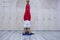 Young attractive yogi woman practicing yoga concept, standing in variation of Pincha Mayurasana exercise, handstand pose, working