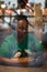 Young authentic black woman sitting with phone in city coffee shop at night