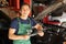 Young auto mechanic with clipboard near car in service center