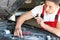 Young auto mechanic repairing car in service center