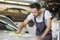 Young automobile mechanic cleaning car in repair shop