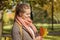 Young autumn woman holding red and yellow maple leaf outdoors. Romantic girl in fall park