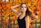 Young autumn woman with yellow leaves background. Outdoor fashion photo of girl beautiful hair surrounded .