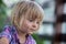 Young baby caucasian blonde girl with dirty face portrait at her family urban vegetable garden