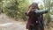 Young backpacker girl with camera taking pictures of forest