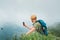 Young backpacker man taking picture of  cloudy valley bottom using smartphone during walking by the foggy cloudy weather mountain