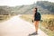 Young backpacking adventurous woman hitchhiking on the road.Traveling backpacks volume,packing essentials.Travel lifestyle