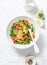 Young baked potato, smoked salmon, green peas and dill salad on light background