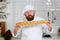 Young baker with beard holds a freshly loaf