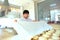 A young Baker covers portions of dough prepared for baking with a white cloth. Yeast dough. The concept of cooking bakery products