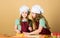 Young bakers following baking recipe. Small bakers rolling paste on kitchen table. Little girls baking cookies in baker