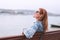 Young balanced redhead woman sitting on bench at riverside meditating