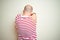 Young bald man with beard wearing casual striped red t-shirt over white isolated background Hugging oneself happy and positive