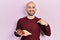 Young bald man eating fresh and healthy fruits pointing finger to one self smiling happy and proud