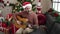 Young bald man playing classical guitar sitting on sofa by christmas tree at home