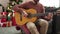 Young bald man playing classical guitar sitting on sofa by christmas tree at home