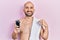 Young bald man shirtless holding electric razor pointing finger to one self smiling happy and proud