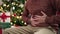 Young bald man sitting by christmas tree suffering stomachache at home