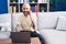 Young bald man talking on smartphone using laptop at home