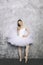 Young ballerina classical ballet dancer using mobile phone against rustic wall