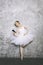 Young ballerina classical ballet dancer using mobile phone against rustic wall