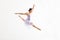Young Ballerina Doing Splits In The Air Against White Background