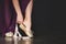 Young Ballerina getting ready for a classical dance. Girl wearing point shoes closeup on the dark background