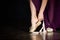 Young Ballerina getting ready for a classical dance. Girl wearing point shoes closeup on the dark background in low key.