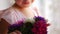 The young ballerina sits on the window and holds flowers in her hands