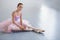 Young ballerina sitting on floor in dancing studio