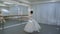 The young ballerina trains to do fouette in front of the mirror with barre in bright ballet class.