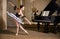 Young ballerina in a white tutu dancing on beautiful old piano in a vintage interior