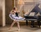 Young ballerina in a white tutu dancing on beautiful old piano in a vintage interior