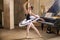 Young ballerina in a white tutu dancing on beautiful old piano in a vintage interior