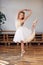 Young ballerina in white tutu practicing dance moves.