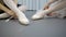 Young ballerinas dressing pointes, sitting in ballet studio.