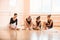 Young ballerinas putting on pointe shoes while sitting on floor