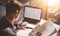 Young banking finance analyst in eyeglasses working at sunny office on laptop while sitting at wooden table.Businessman