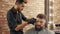 Young barber grooming handsome male client in barbershop