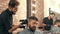 Young barber trimming hair to handsome bearded client in barbershop