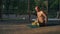 Young barefoot guy with naked torso performs yoga asan on wood aide early in the morning in city park