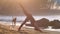 Young barefoot woman changes yoga pose on sandy beach