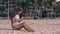 Young barefoot woman in gray texts on phone sitting on sand