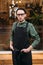 Young barman in black apron