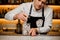 Young barman stirring ice cubes in a glass