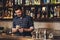 Young bartender standing at bar counter counting salary happy