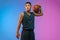 Young basketball player in motion on gradient studio background in neon light