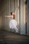 Young bayerina in a long white skirt stands in a graceful pose on pointes